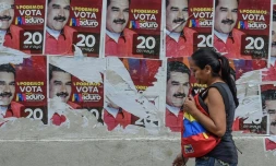 Une femme devant des affiches de campagne du président vénézuélien Nicolas Maduro, à Caracas le 19 mai 2018