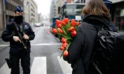 Une femme arrive avec des fleurs à la station de métro de Maelbeek le 23 mars 2016 à Bruxelles
