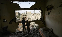 Des enfants dans les ruines d'un immeuble regardent les bâtiments détruits par des frappes israéliennes, le 21 mai 2021 à Gaza