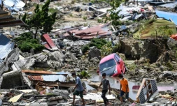 Des rescapés passent au milieu des décombres d'habitations à Palu le 2 octobre 2018, frappé par un séisme et un tsunami le 28 septembre.