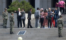 Des soldats nord-coréens montent la garde du cÎté nord du la frontiÚre tandis que des touristes visitent le village de Panmounjom