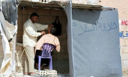 Un réfugié irakien qui a fui la ville Mossoul, sous contrôle de l'EI, rase la barbe d'un autre réfugié dans le camp Al-Hol, à Al-Hawl, en Syrie, le 25 octobre 2016