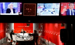 Le président français et candidat à sa réélection Emmanuel Macron répond aux questions de la journaliste Lea Salame (gauche) et du journaliste Nicolas Demorand (centre), sous un écran de télévision montrant la candidate du Rassemblement national à la présidentielle Marine Le Pen (en haut), lors d'une interview sur le 7/9, émission matinale de France Inter le 4 avril 2022 à Paris