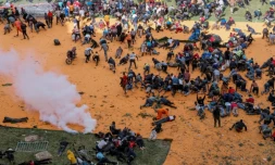Des partisans et personnes en deuil se mettent à l'abri aprÚs que des coups de feu et des gaz lacrymogÚnes ont été tirés lors d'un rassemblement pour l'exposition publique du cercueil du leader de l'opposition kenyan Raila Odinga au stade Kasarani à Nairobi, le 16 octobre 2025, au lendemain de son décÚs en Inde