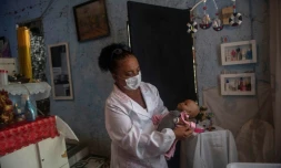 Suelen da Silva ausculte sa patiente, une poupée; qu'elle va restaurer, chez elle dans son "hopital de poupées" à Niteroi, près de Rio de Janeiro, le 10 décembre 2020