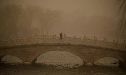 Une femme traverse un pont pendant une tempête de sable à Pékin le 15 mars 2021