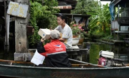 Nopadol, postier, distribue des lettres et colis aux habitants vivant sur les bords d'un canal dans la province de Bang Khun Thian, près de Bangkok en Thaïlande, le 17 juillet 2017