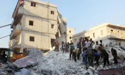 Des habitants et des casques blancs cherchent des survivants le 29 septembre 2017 sous les décombres d'un bâtiment détruit par une frappe aérienne à Harim (nord-ouest) dans la province d'Idlib