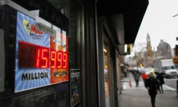 Des gens passent devant un écran de loterie Powerball à New York le 12 janvier 2016