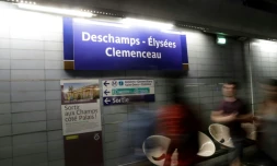 Des passagers du métro de Paris marchent devant l'affiche "Deschamps - Elysées Clemenceau", référence au nom de l'entraîneur de l'équipe de France de football Didier Deschamps, à la station de Champs - Elysées Clemenceau le 16 juillet 2018