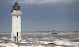 Un bateau de pêche passe le 9 février 2020 devant le phare de New Brighton, dans le nord-ouest de l'Angleterre, où la tempête Ciara est arrivée