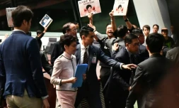 La cheffe de l'exécutif hongkongais Carrie Lam (c) quitte le Parlement local après avoir été chahutée par des parlementaires, le 16 octobre 2019