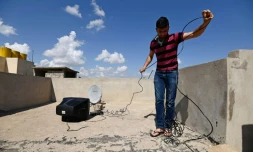 Mohammad Turki installe une parabole sur le toit d'une maison à Mossoul-Est, le 15 avril 2017