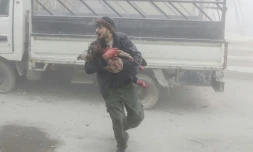 Un Syrien fuit avec un enfant les frappes du régime syrien dans la localité de Saqba, dans la Ghouta orientale, le 6 février 2018