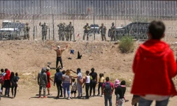 Des migrants cherchant à entrer aux Etats-Unis devant une barrière de fil barbelé et des agents de la Garde nationale du Texas, à la frontière entre le Mexique et les Etats-Unis, à Ciudad Juarez, le 13 mai 2024