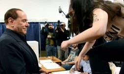 Une militante Femen saute sur une table devant Silvio Berlusconi, , proclamant sur son torse nu "Berlusconi, tu es périmé", le 4 mars 2018 dans un bureau de vote à Milan
