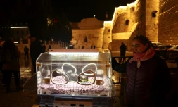 L'artiste palestinienne Rana Bishara devant son installation représentant l'enfant Jésus dans une couveuse, devant l'église de la Nativité à Bethléem le 24 décembre 2023
