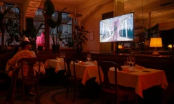 La cérémonie d'ouverture des Jeux olympiques de Paris 2024 passe sur un écran de télévision dans un restaurant à Paris, le 26 juillet 2024