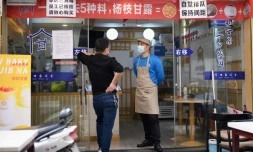 Des employés d'un restaurant munis de masques de protection contre le coronavirus attendent le client à Huanggang, dans la province chinoise du Hubei, le 26 mars 2020 