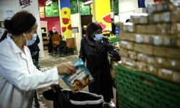 Une bénévole des Restos du coeur distribue une aide alimentaire à des personnes dans le besoin, le 13 octobre 2020 à Paris