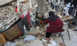 Une Palestinienne prépare un repas sur un poêle de fortune au milieu des décombres d'un bâtiment, le 9 mars 2025 dans le nord de la bande de Gaza