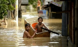 Des enfants dans une rue inondée le 18 décembre 2015 à Candaba aux Philippines
