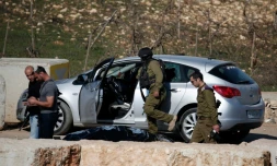 Des soldats israéliens contrÎlent le 11 décembre 2015 la voiture d'un Palestinien, abattu dans une tentative d'attaque anti-israélienne à la voiture-bélier au check-point de Halhul, au nord de Hébron, en Cisjordanie