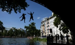 Des jeunes sautent d'un pont dans le canal Saint-Martin lors d'une vague de chaleur à Paris, le 22 juin 2026