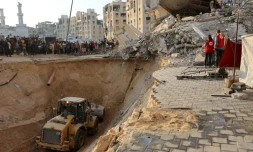 Des habitants et des membres de la Croix rouge regardent un tractopelle creuser, selon les autorités locales pour chercher les corps des otages, le 17 octobre 2025 à Khan Yunes