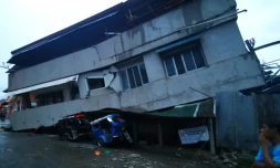 Des habitants observent une maison détruite avec un véhicule coincé dessous après un puissant séisme, à Padada dans la province de Davao del Sur sur l'île de Mindanao aux Philippines le 15 décembre 2019