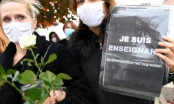Deux femmes portent des roses et des messages en faveur de la liberté d'expression le 17 octobre 2020 à Conflans-Sainte-Honorine