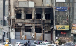 Des passants le 19 janvier 2026 devant un immeuble détruit lors des manifestations à Téhéran, en Iran