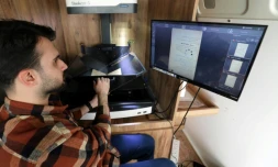 Un membre du Centre des arts et de la culture du Kurdistan (KCAC)scanne les pages d'un livre ancien pour en faire une copie numérique, le 13 février 2024 à Dohouk, dans la région du Kurdistan autonome, dans le nord de l'Irak