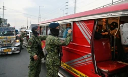 Un policier philippin inspecte un bus à Manille, le 15 mars 2020