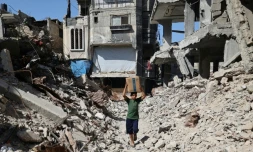 Un garçon palestinien déplacé porte une boîte de fournitures d'urgence fournies par le Programme alimentaire mondial (PAM) après l'avoir reçue d'un point de distribution d'aide au camp de réfugiés de Nuseirat dans le centre de la bande de Gaza, le 19 octobre 2025