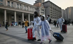 Des passagers portant des masques et des combinaisons pour se protéger se rendent à la gare de Wuhan, dans le centre de la Chine, le 8 avril 2020, après la levée des restrictions pour quitter la ville, berceau de la pandémie de coronavirus.

