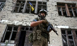 Un soldat ukrainien devant le centre culturel endommagé de Blagodatné, récemment libéré, où flotte le drapeau ukrainien, le 16 juin 2023 dans la région de Donetsk