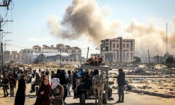 Des Palestiniens fuient Khan YounÚs dans le sud de la bande de Gaza, avec en arriÚre-plan un nuage de fumée s'élevant aprÚs des bombardements, le 30 janvier 2024