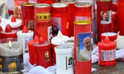 Des bougies déposées au pied de la statue de Jean-Paul II devant l'hôpital Gemelli à Rome où le pape François est soigné pour une pneumonie, le 14 mars 2025
