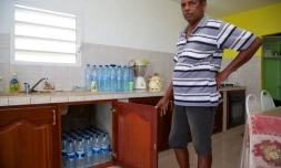 Un homme dans sa cuisine remplie de bouteilles d'eau pour faire face aux coupures d'eau à Capesterre, en Guadeloupe, le 26 juillet 2018