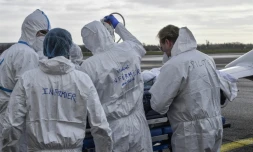 Une équipe médicale entoure un brancard occupé par un malade du Covid-19, le 16 novembre 2020 sur le tarmac de l'aéroport de Bron, prÚs de Lyon