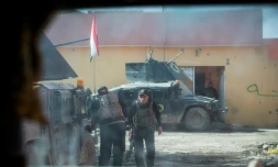 Une photo prise par la fenêtre blindé montre des soldats de la 2ème division des forces spéciales irakiennes se couvrant derrière leurs véhicules sous le feu d'un tireur de l'EI, le 12 novembre 2016, dans le quartier Al-Samah, à l'est de Mossoul