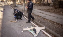 Des policiers ukrainiens inspectent un drone russe abattu dans les environs de l'Académie nationale des sciences, touchée par une frappe, à Kiev, le 22 mars 2022