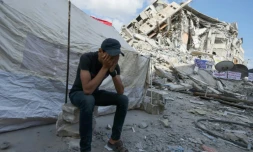 Un Palestinien couvre son visage avec les mains, assis devant une tente installée au milieu des décombres dans la bande de Gaza, le 23 mai 2021