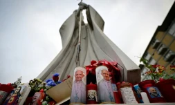 Des bougies à l'effigie du pape François et de Padre Pio déposées au pied de la statue de Jean Paul II devant l'hôpital Gemelli où le pape François est hospitalisé, le 19 février 2025 à Rome