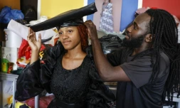 Le styliste McBright Kavari ajuste un chapeau otjikaiva sur une mannequin dans son atelier à Windhoek, le 30 novembre 2024 en Namibie