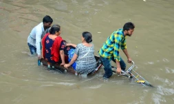 Des habitants traversent une route inondée après de fortes pluies à Mathura, dans l'Etat indien de l'Uttar Pradesh, le 26 juillet 2018.