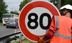 Un employé de la Direction interdépartementale des routes (DIR) installe un panneau de limitation de vitesse à 80 km/h sur une route nationale