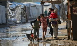 Des Palestiniens marchent dans une zone inondée après de fortes pluies dans un camp de déplacés à Deir el-Balah, dans le centre de la bande de Gaza, le 30 décembre 2024