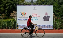 Un cycliste passe devant un panneau montrant le Premier ministre indien Narendra Modi, installé en amont du sommet des Brics, à New Delhi, le 9 septembre 2026